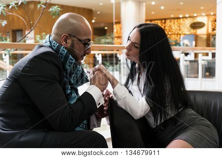 Arab man and the stylish girl sitting and holding hands in an airport lounge