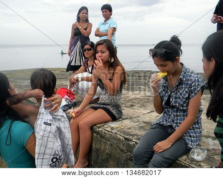 CEBU CITY, CEBU / PHILIPPINES - JULY 30, 2011: People enjoy eating sliced pineapple at a picnic at the seashore of Cebu.