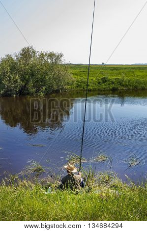 The river Kargat Novosibirsk oblast Siberia Russia - June 12 2016: a fisherman catches a fish on the river on a float