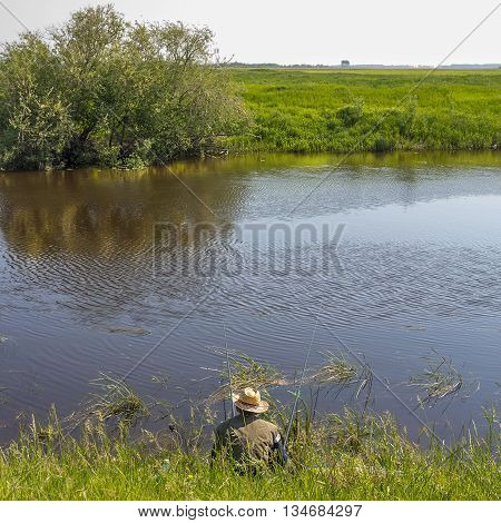 The river Kargat Novosibirsk oblast Siberia Russia - June 12 2016: a fisherman catches a fish on the river on a float
