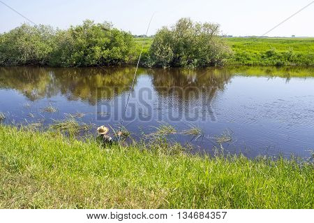 The river Kargat Novosibirsk oblast Siberia Russia - June 12 2016: a fisherman catches a fish on the river on a float