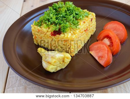 Central Asian traditional dish - pilaf (plov risotto) in the form of a square decorated with chopped parsley in clay bowl on a light wooden background.