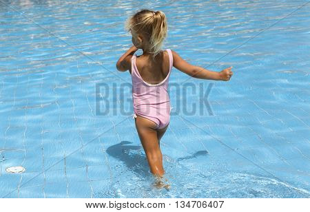 Beautiful little girl in a blue swimming pool water