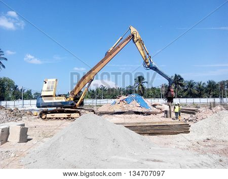 SELANGOR, MALAYSIA -MARCH 25, 2015: Sheet pile cofferdam driven machine at the construction site. The machine drove the sheet pile to the earth using vibrated hydraulic arm. Workers control.