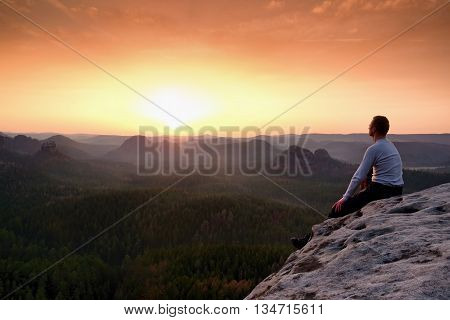 Man Sit On Peak. Colorful Mist And Fog In Forest Valley Bellow.