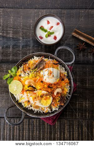 Basmati rice slowly cooked with Masala roasted egg and spices served in kadhai or kadai with yogurt dip, selective focus, egg biryani or anda rice or egg rice