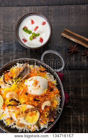 Basmati rice slowly cooked with Masala roasted egg and spices served in kadhai or kadai with yogurt dip, selective focus, egg biryani or anda rice or egg rice