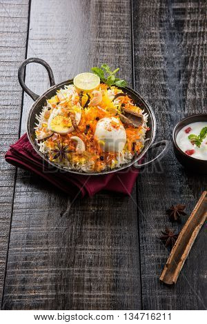 Basmati rice slowly cooked with Masala roasted egg and spices served in kadhai or kadai with yogurt dip, selective focus, egg biryani or anda rice or egg rice