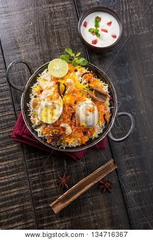 Basmati rice slowly cooked with Masala roasted egg and spices served in kadhai or kadai with yogurt dip, selective focus, egg biryani or anda rice or egg rice