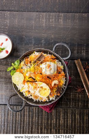 Basmati rice slowly cooked with Masala roasted egg and spices served in kadhai or kadai with yogurt dip, selective focus, egg biryani or anda rice or egg rice