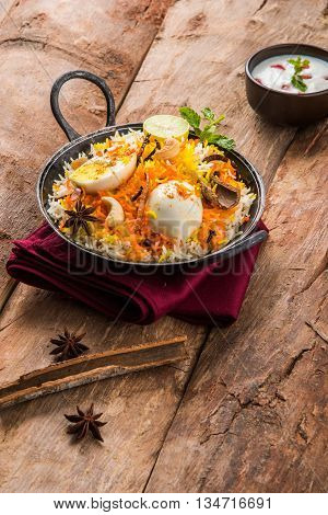 Basmati rice slowly cooked with Masala roasted egg and spices served in kadhai or kadai with yogurt dip, selective focus, egg biryani or anda rice or egg rice
