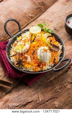 Basmati rice slowly cooked with Masala roasted egg and spices served in kadhai or kadai with yogurt dip, selective focus, egg biryani or anda rice or egg rice