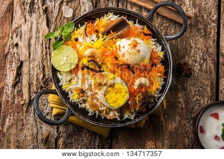 Basmati rice slowly cooked with Masala roasted egg and spices served in kadhai or kadai with yogurt dip, selective focus, egg biryani or anda rice or egg rice