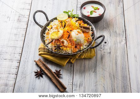 Basmati rice slowly cooked with Masala roasted egg and spices served in kadhai or kadai with yogurt dip, selective focus, egg biryani or anda rice or egg rice