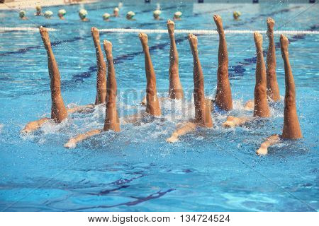 Synchronized swimmers legs movement. Synchronized swimming team performing a synchronized routine of elaborate moves in the water.