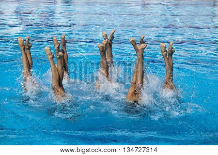 Synchronized swimmers legs movement. Synchronized swimming team performing a synchronized routine of elaborate moves in the water.