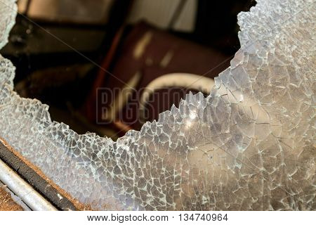 Cracked car windshield with hole in the middle