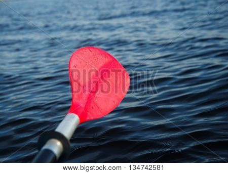 red paddle or oar of boat with dark lake background