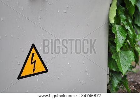 Yellow high voltage sign with rain leaf contrast photo