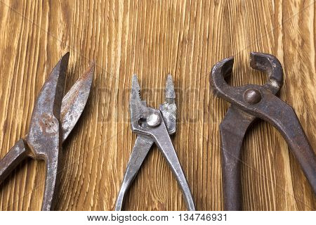 Heap of old instruments on wooden background. Pliers and scissors on wooden background.
