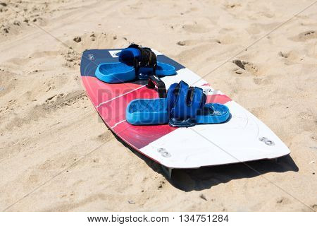Windsurfing board with sail lying on the sand and windless sea