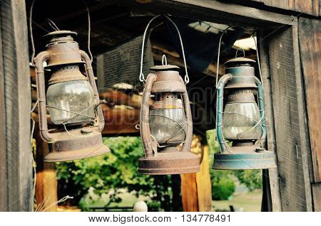 Three old oil lamps hanging outside a barn