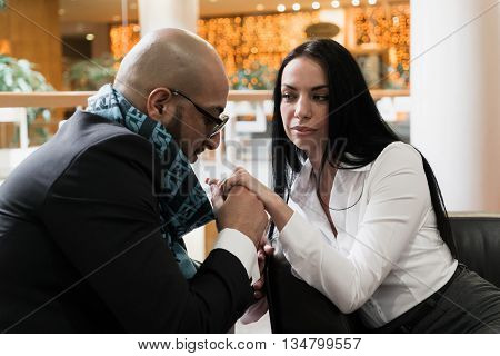 Arab man and the stylish girl sitting and holding hands in an airport lounge