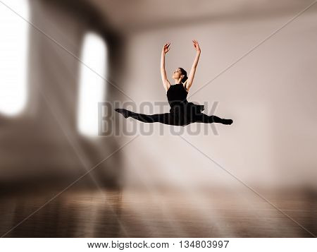 Young pretty ballerina making jump in dance in studio