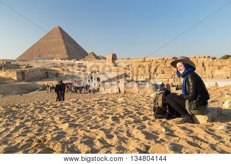 Tourist sitting on the stone at The Giza pyramid complex.