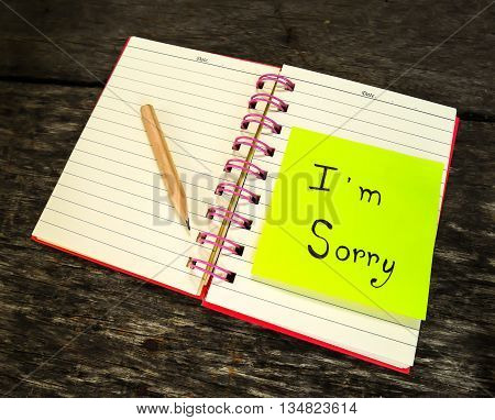 Sorry paper note in note book on wooden table