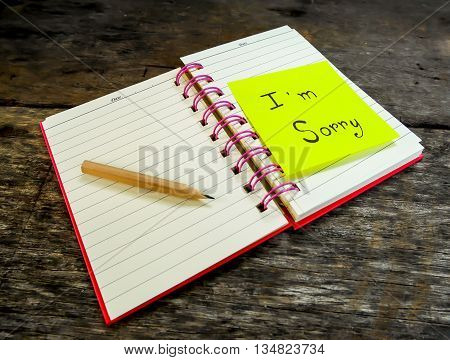 Sorry paper note in note book on wooden table