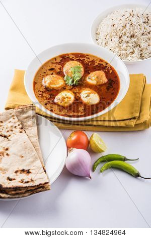 egg curry with roti/chapati and jeera rice, tasty and spicy anda curry with roti and rice, indian egg masala curry served in ceramic bowl with roti, salad and jeera rice