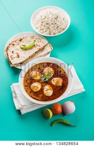 egg curry with roti/chapati and jeera rice, tasty and spicy anda curry with roti and rice, indian egg masala curry served in ceramic bowl with roti, salad and jeera rice