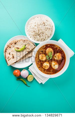 egg curry with roti/chapati and jeera rice, tasty and spicy anda curry with roti and rice, indian egg masala curry served in ceramic bowl with roti, salad and jeera rice