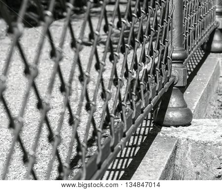 indistinct fragment of an old iron fence closeup in park in outdoor and a blank space of monochrome tone