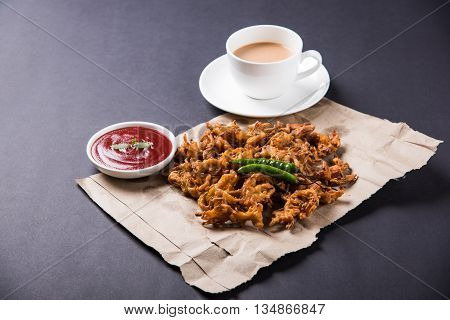 Crispy onion bhaji or kanda bhaji or fried onion pakore or pakode, delicious street food, favourite indian snack in monsoon served with hot tea