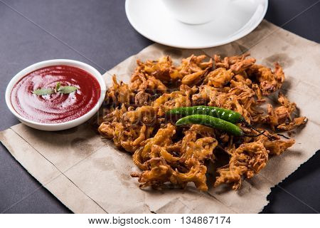 Crispy onion bhaji or kanda bhaji or fried onion pakore or pakode, delicious street food, favourite indian snack in monsoon served with hot tea