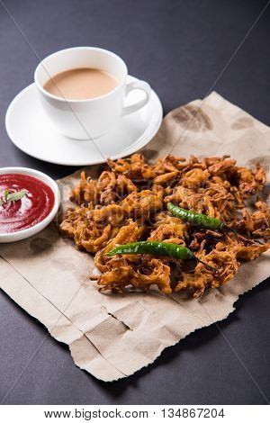 Crispy onion bhaji or kanda bhaji or fried onion pakore or pakode, delicious street food, favourite indian snack in monsoon served with hot tea