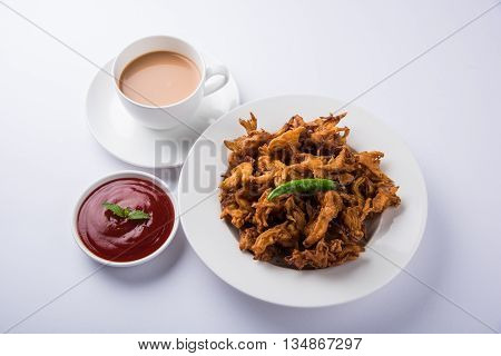 Crispy onion bhaji or kanda bhaji or fried onion pakore or pakode, delicious street food, favourite indian snack in monsoon served with hot tea