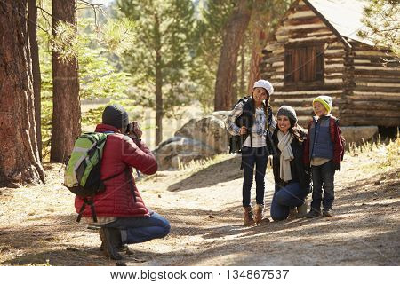 Family taking a photo in front of a log cabin in a forest