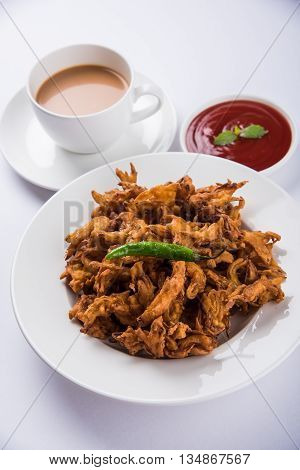 Crispy onion bhaji or kanda bhaji or fried onion pakore or pakode, delicious street food, favourite indian snack in monsoon served with hot tea