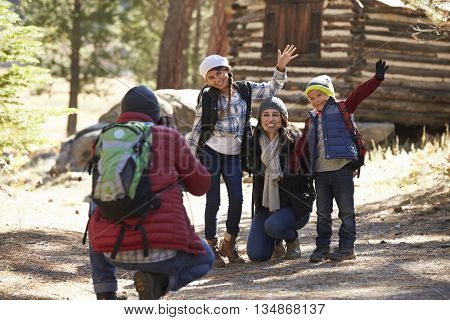 Family taking a photo in front of a log cabin, close up