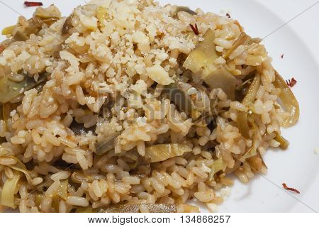 Brown rice with carciofi and grated cheese on the plate close-up.