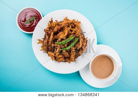 Crispy onion bhaji or kanda bhaji or fried onion pakore or pakode, delicious street food, favourite indian snack in monsoon served with hot tea