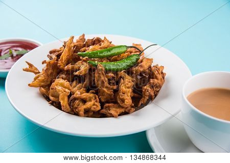 Crispy onion bhaji or kanda bhaji or fried onion pakore or pakode, delicious street food, favourite indian snack in monsoon served with hot tea