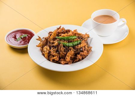 Crispy onion bhaji or kanda bhaji or fried onion pakore or pakode, delicious street food, favourite indian snack in monsoon served with hot tea