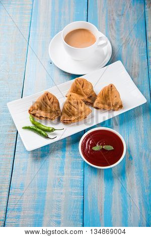 Samosa snack with tomato ketchup and hot tea, Fresh samosas with ketchup and hot chai ready for breakfast