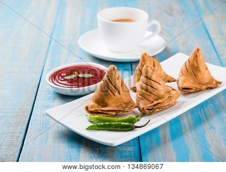 Samosa snack with tomato ketchup and hot tea, Fresh samosas with ketchup and hot chai ready for breakfast