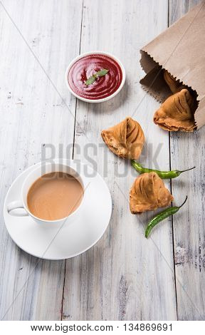 Samosa snack with tomato ketchup and hot tea, Fresh samosas with ketchup and hot chai ready for breakfast