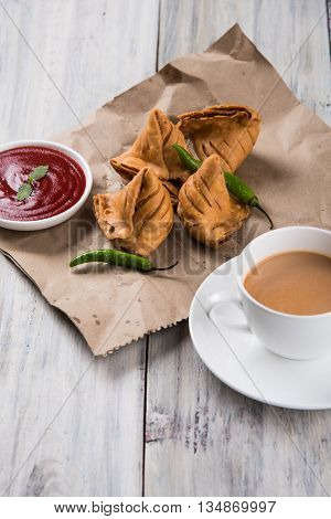Samosa snack with tomato ketchup and hot tea, Fresh samosas with ketchup and hot chai ready for breakfast